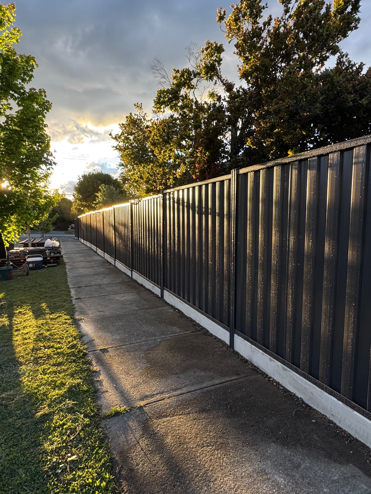 Black Colorbond fence line at sunset with concrete plinths