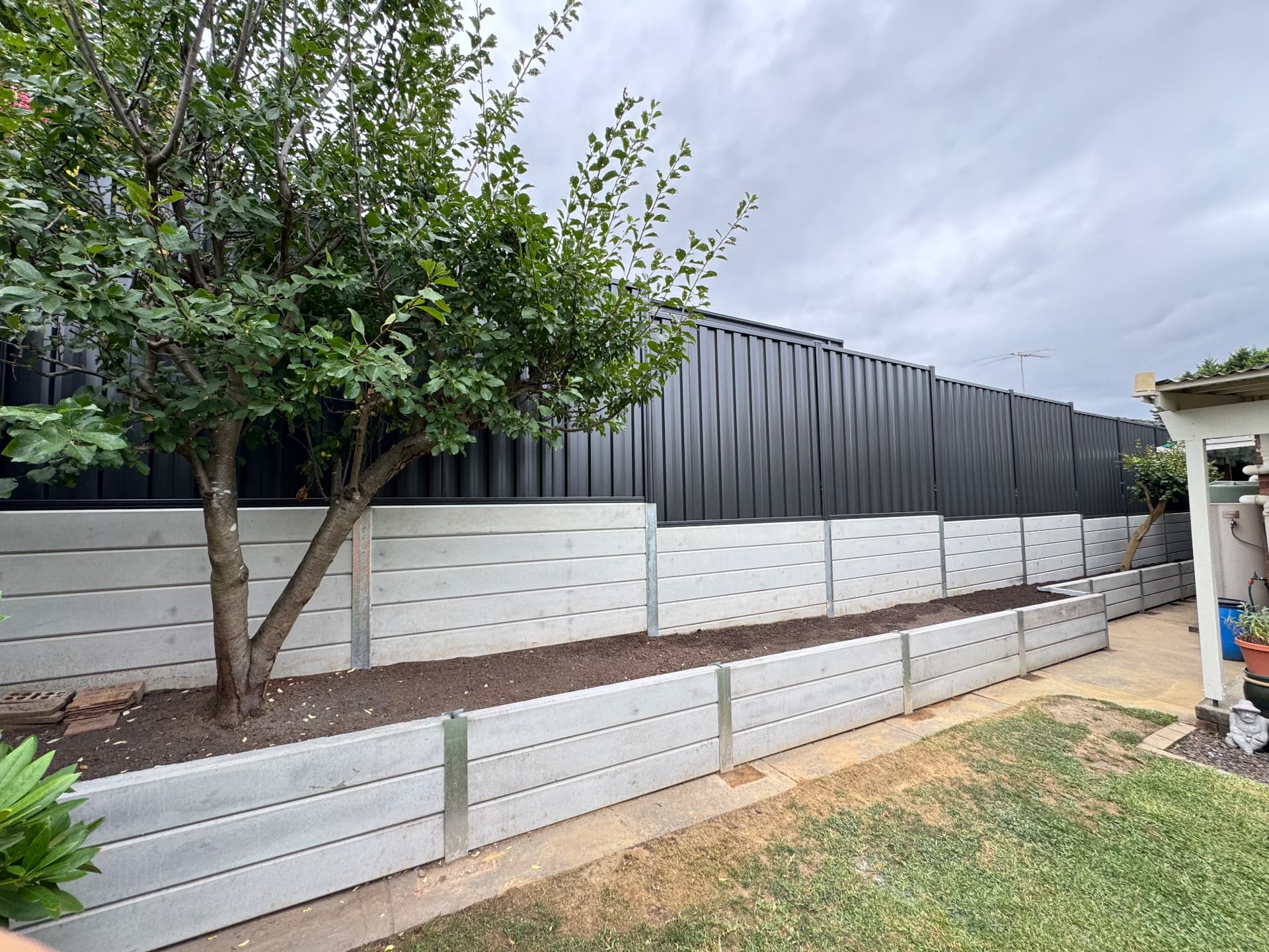 Tiered concrete sleeper retaining wall with galvanised steel posts and garden beds